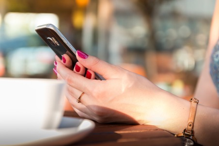 Plan sur des mains consultant un smartphone à la table d'un café