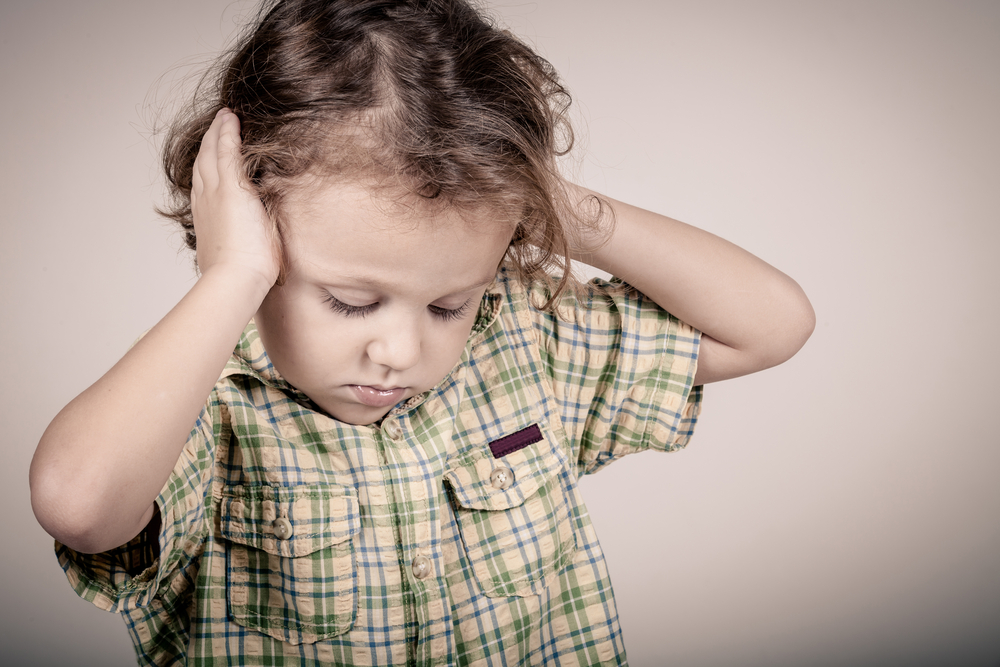 Jeune enfant autiste se mettant les mains sur les oreilles