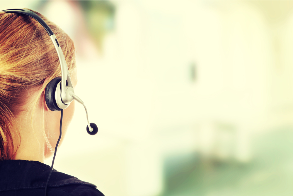 Femme blonde de dos avec un casque téléphonique sur la tête