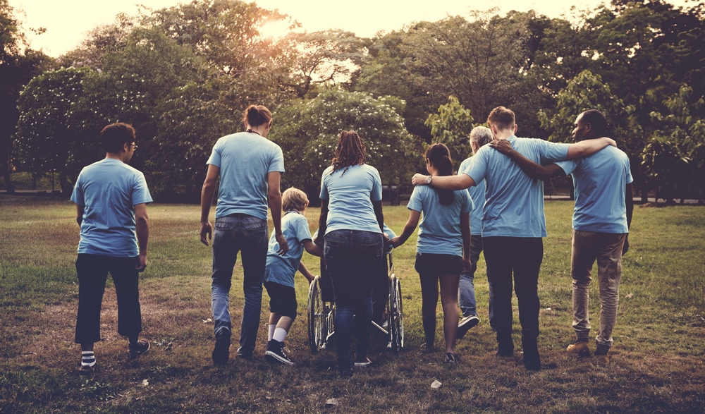 6 personnes de dos, dont une personne en fauteuil marchant ensemble