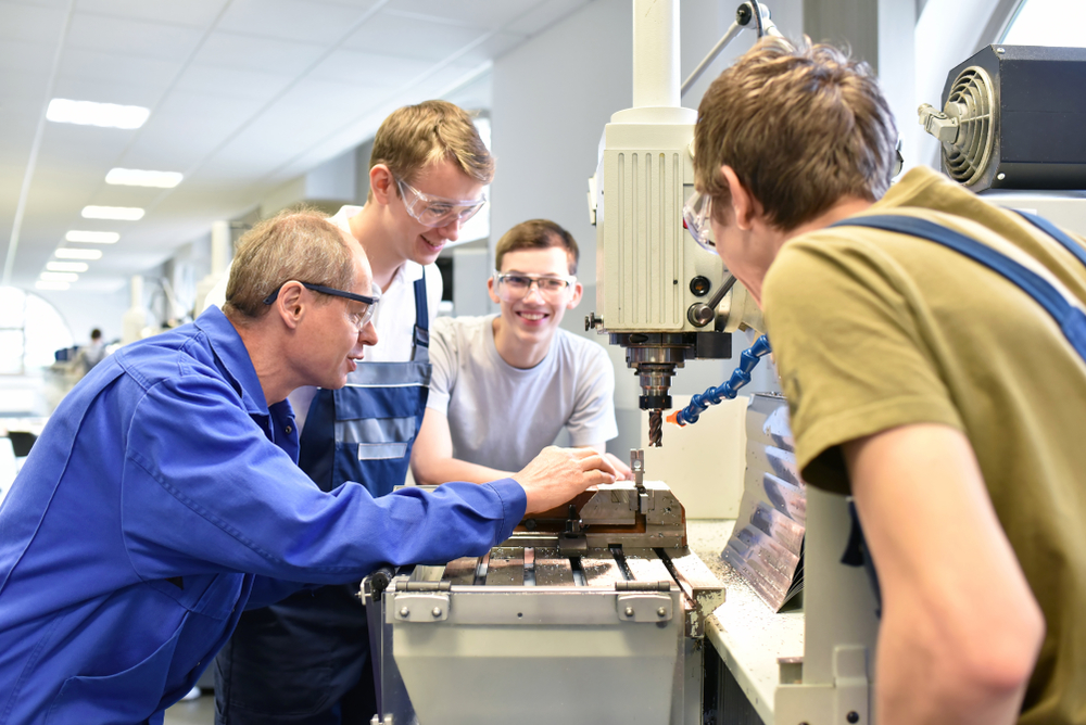 professeur montrant à des élèves le fonctionnement d'une machine en atelier