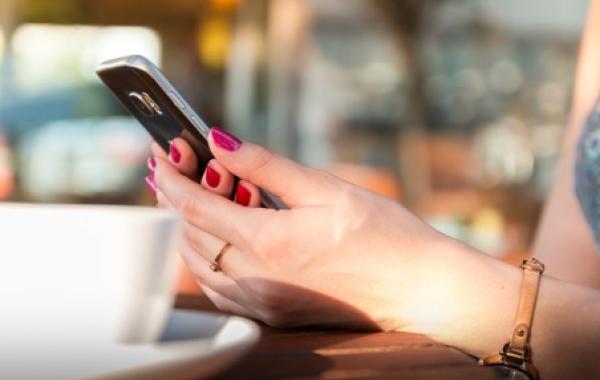 Plan sur des mains consultant un smartphone à la table d'un café