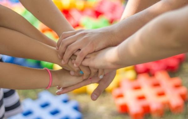 mains d'enfants réunies au centre avec pièces de couleurs en arrière plan