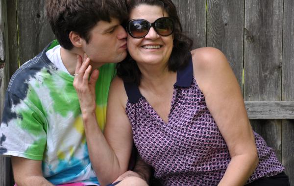 Jeune adulte autiste qui embrasse la joue d'une femme brune