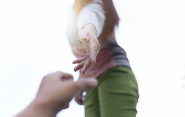 main de femme tendue vers une main d'homme au premier plan