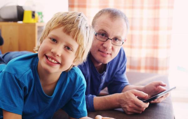 Garçonnet blond autiste avec son père qui consulte une tablette