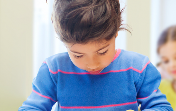 Petite fille brune consultant une tablette sur une table devant elle