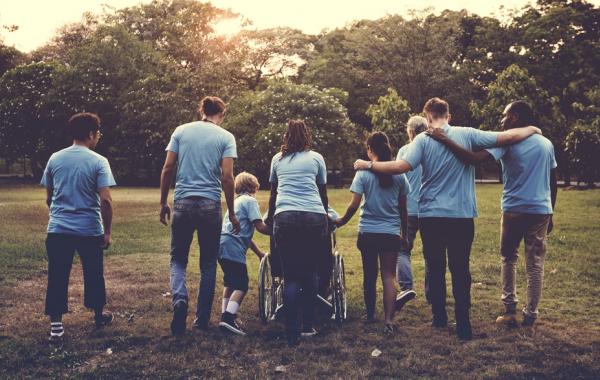 6 personnes de dos, dont une personne en fauteuil marchant ensemble