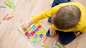 enfant pris de haut qui joue au sol avec des lettres de couleurs
