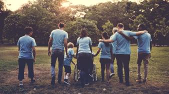 6 personnes de dos, dont une personne en fauteuil marchant ensemble