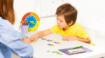 Photo d'un enfant face à une enseignante avec time timer et planning visuel